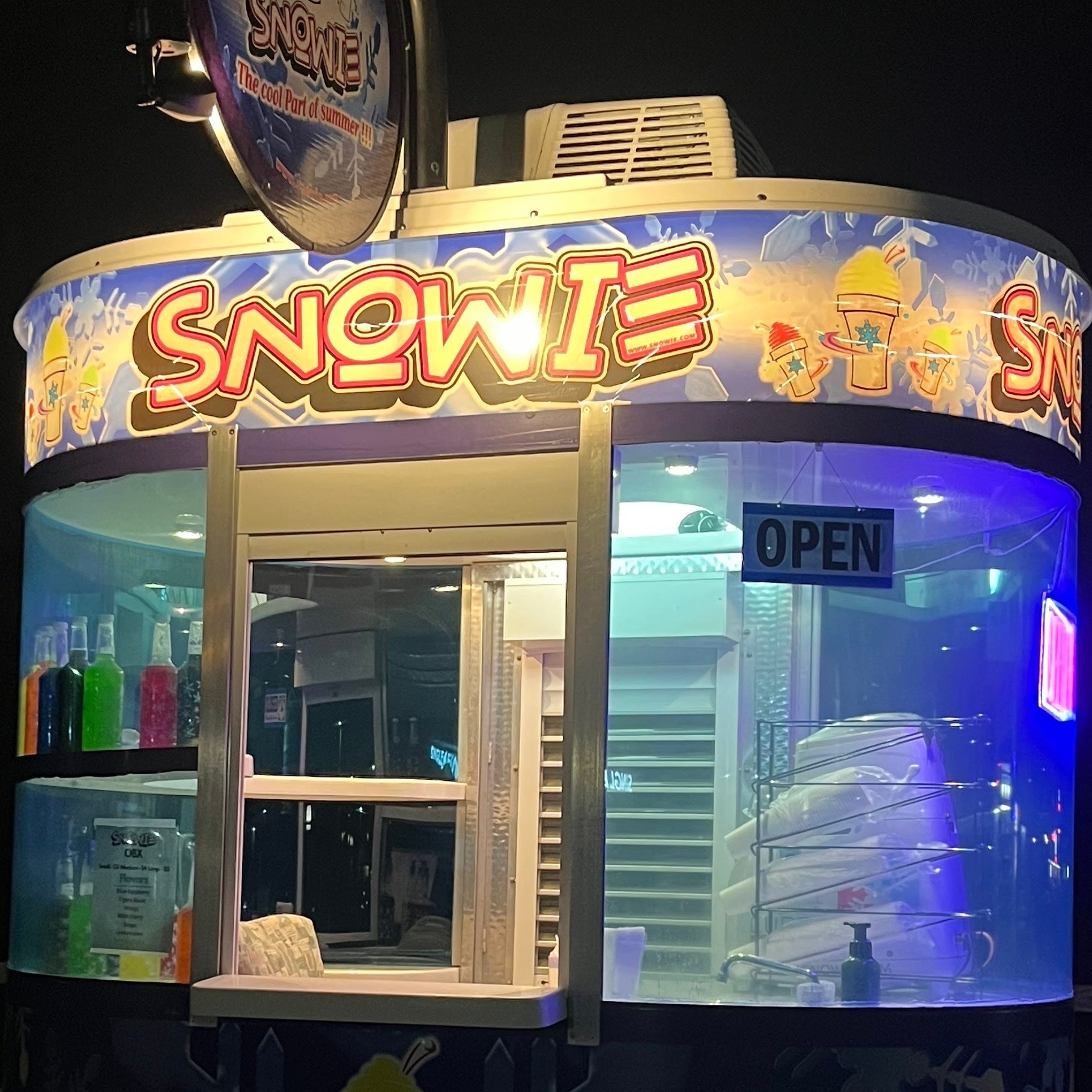 Snowie Shaved Ice trailer lit at night showing bottles of flavor