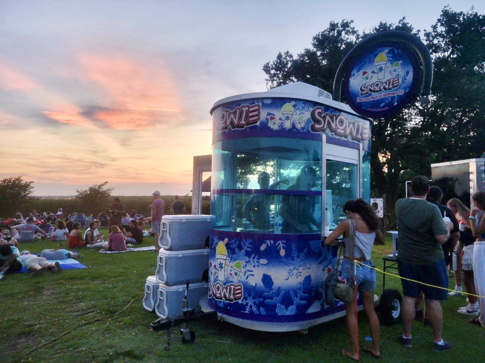Shaved Ice trailer at festival with people and sunset